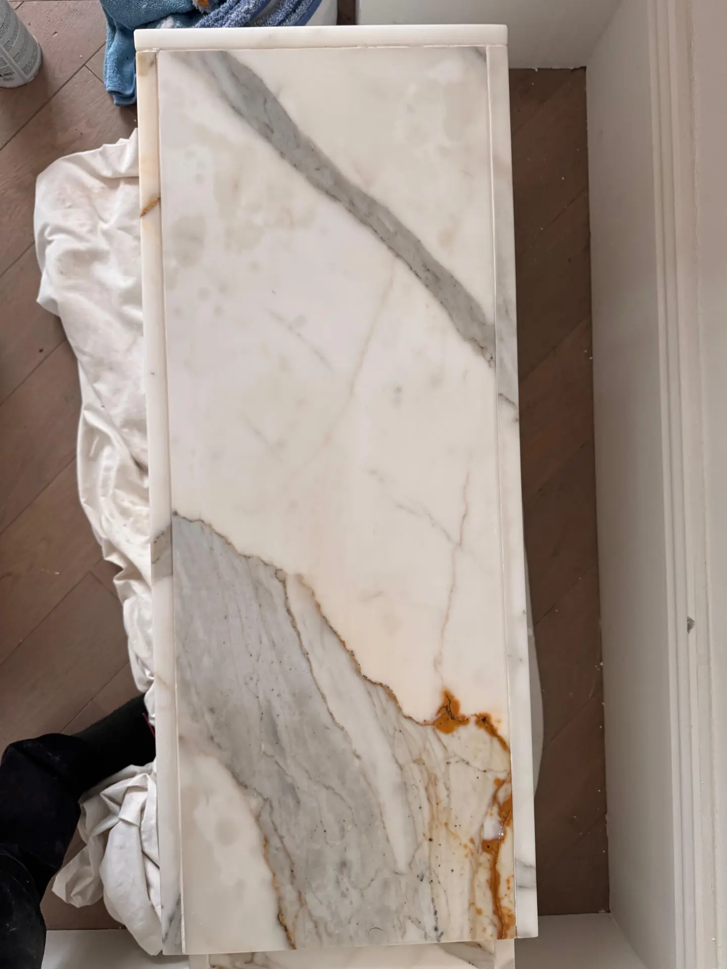 Marble plinth part-way through oil stain removal, with the dark patches noticeably lighter after poultice treatment
