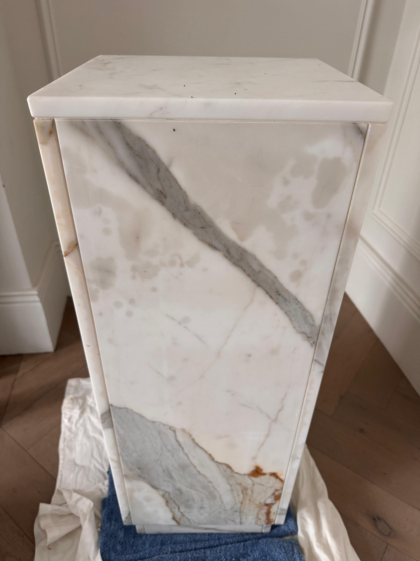 Marble plinth with a deep oil stain absorbed into the stone, before restoration