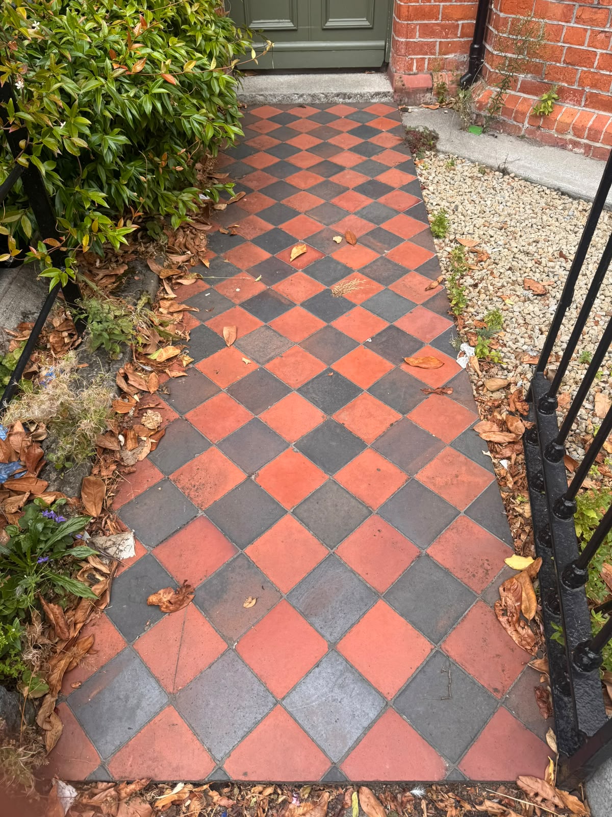 Red and black Victorian quarry tile garden path before restoration — dulled, dirty and covered in fallen leaves